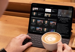 Ein Mann nutzt ein Tablet beim Kaffee trinken