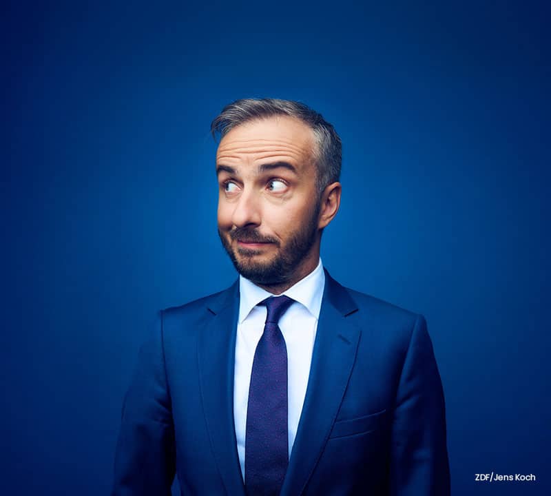 Jan Böhmermann im blauen Anzug vor blauem Hintergrund.