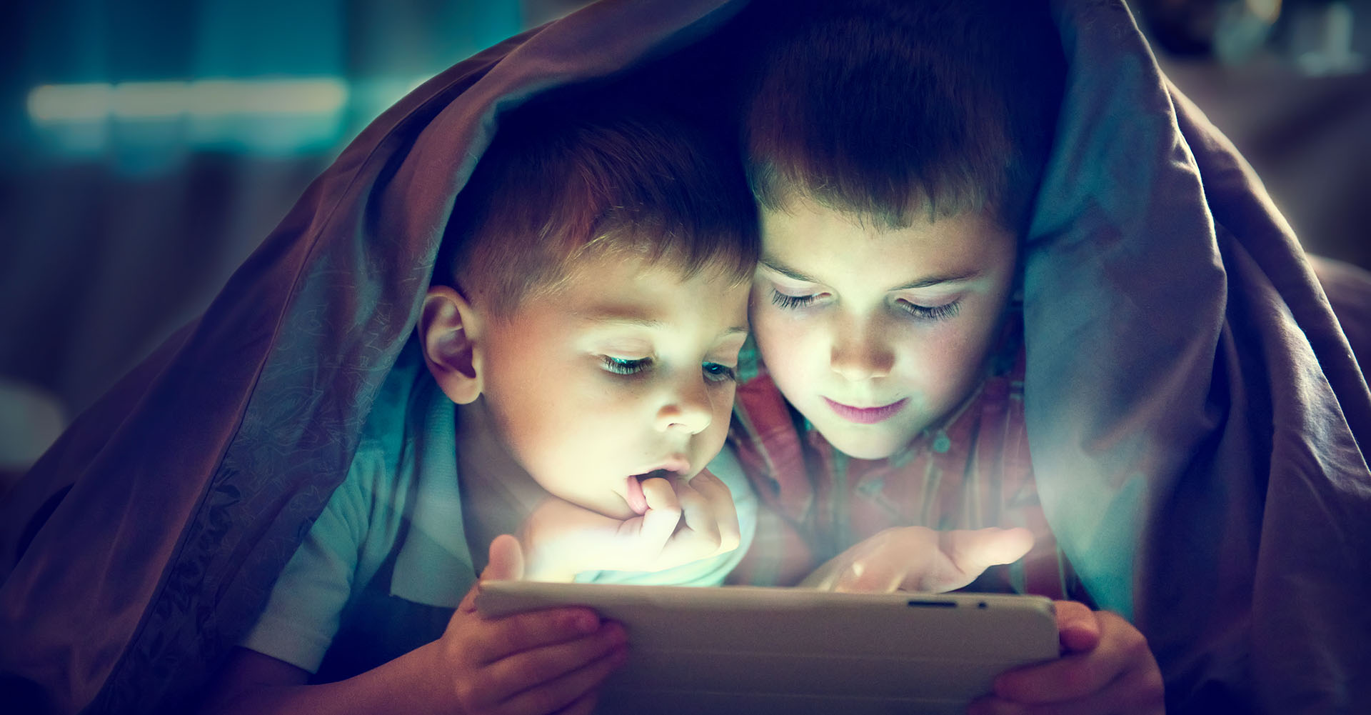 Zwei Jungs schauen gemeinsam fern auf einem Tablet.